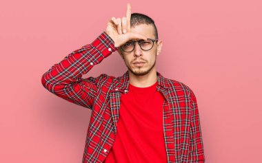 İspanyol genç adam gündelik kıyafetler giyiyor. Alnında parmakları olan insanlarla dalga geçiyor. Ezik hareketler yapıyor, alay ediyor ve hakaret ediyor.. 