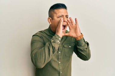 Gündelik kıyafetler giyen genç latin adam elleri ağızda bağırarak bağırıyor. 