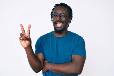 Saçları örgülü, neşeli yüzüyle gülümseyen, zafer işareti yapan Afro-Amerikan genç bir adam. İki numara.. 