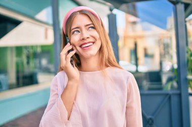 Beyaz kız gülümsüyor. Şehirdeki akıllı telefondan konuşuyor..