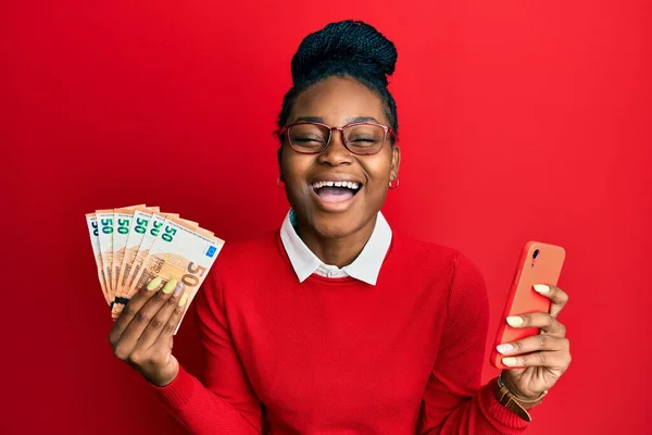 Mujer Afroamericana Joven Usando Teléfono Inteligente Con Billetes Euros Sonriendo —  Fotos de Stock