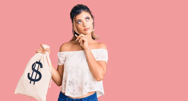 Young Beautiful Woman Holding Money Bag Dollar Symbol Serious Face — Stock Photo, Image