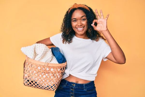 若いアフリカ系アメリカ人女性が指でOkサインを行う洗濯バスケットを保持し 優しいジェスチャー優れたシンボルを笑顔 — ストック写真