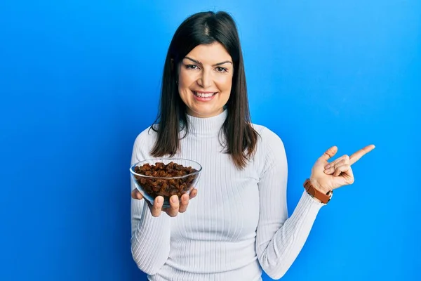 Mujer Hispana Joven Sosteniendo Cuenco Pasas Sonriendo Feliz Señalando Con — Foto de Stock