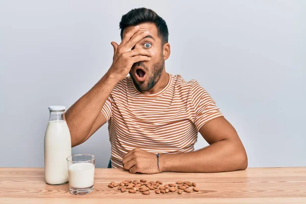 Bello Ispanico Che Beve Latte Mandorla Sano Sbirciando Sotto Shock — Foto Stock