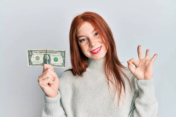 Young Red Head Girl Holding Dollar Banknote Doing Sign Fingers — Stockfoto