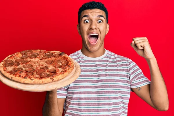 Jovem Árabe Homem Segurando Pizza Italiana Gritando Orgulhoso Celebrando Vitória — Fotografia de Stock