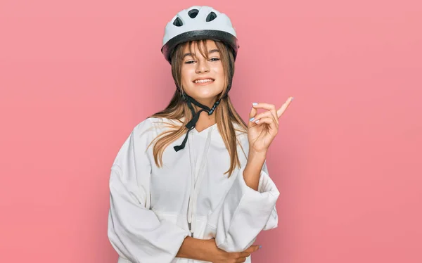 若いですCaucasian女の子身に着けています自転車ヘルメットで大きな笑顔で顔 カメラを見て側に手と指で指して — ストック写真