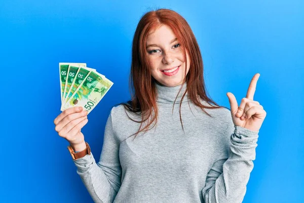 Menina Cabeça Vermelha Jovem Segurando Shekels Israel Notas Sorrindo Feliz — Fotografia de Stock