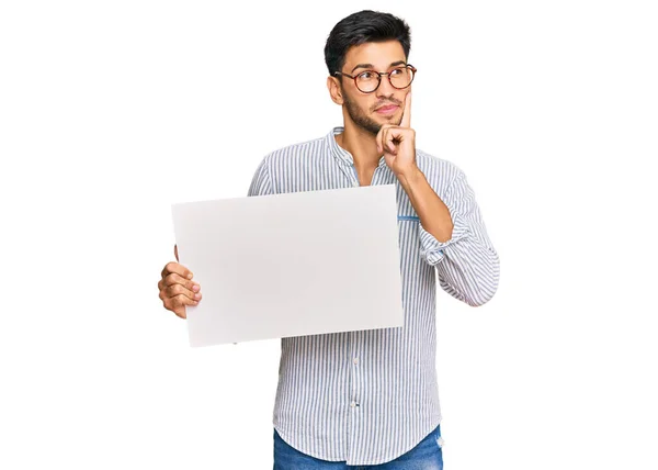 Jovem Homem Bonito Segurando Banner Vazio Vazio Rosto Sério Pensando — Fotografia de Stock