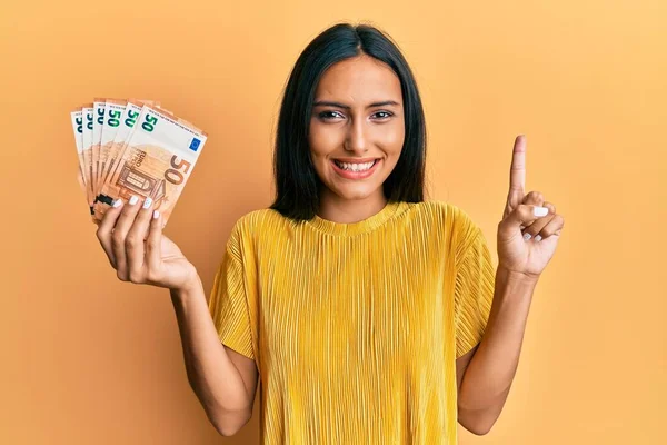 Молодая Брюнетка Банкнотами Евро Улыбающаяся Идеей Вопросом Указывающая Пальцем Счастливым — стоковое фото