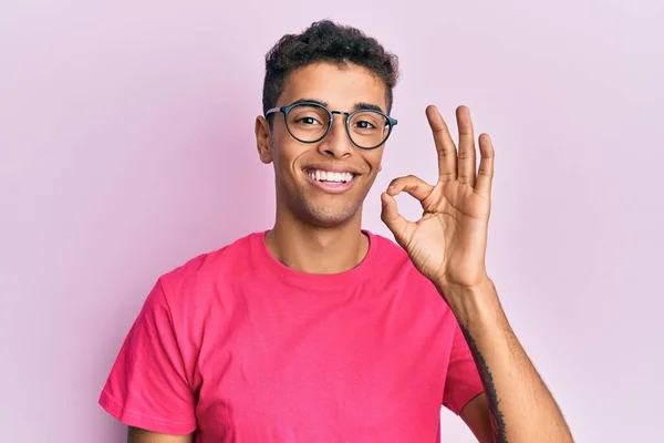 분홍색 안경을 아프리카계 미국인이 손가락으로 괜찮은 사인을 하면서 긍정적 미소를 — 스톡 사진