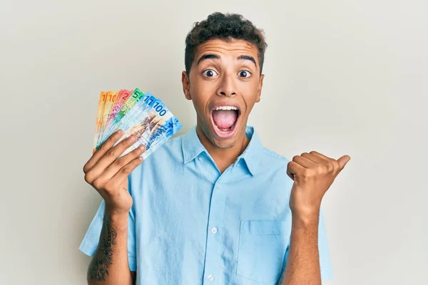 Joven Hombre Afroamericano Guapo Sosteniendo Billetes Suizos Franco Apuntando Con —  Fotos de Stock
