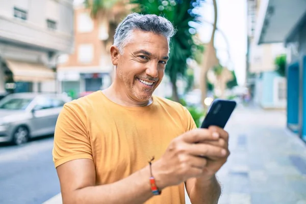 Medelålders Gråhårig Man Ler Glad Med Smartphone Promenader Gatan Staden — Stockfoto