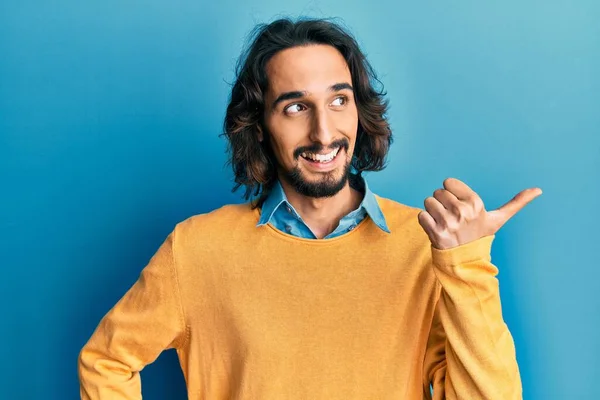 Jovem Hispânico Vestindo Roupas Casuais Apontando Polegar Para Lado Sorrindo — Fotografia de Stock