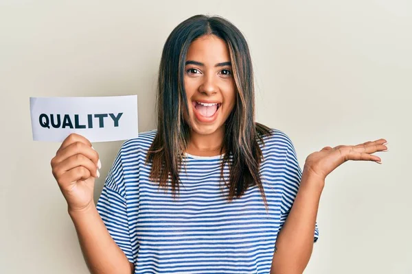 Young Latin Girl Holding Quality Word Paper Celebrating Victory Happy — Stock Photo, Image