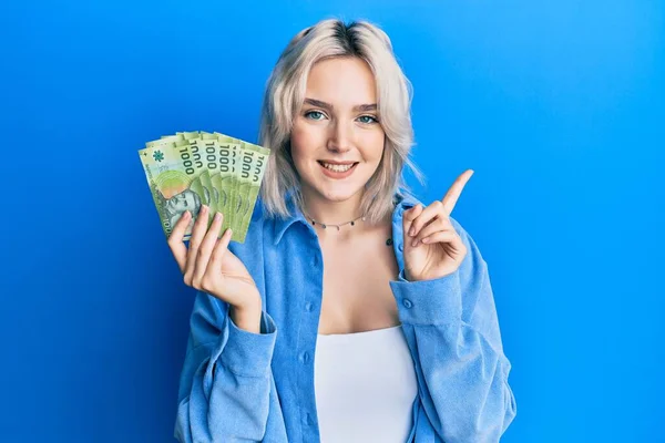 Mladá Blondýnka Drží 1000 Chilských Pesos Úsměvem Šťastný Ukazující Rukou — Stock fotografie