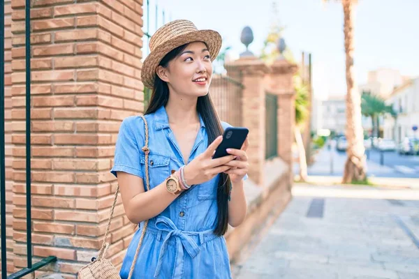 Young chinese tourist woman using smartphone at street of city.