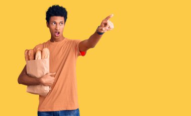 Genç Afro-Amerikan bir adam elinde kağıt torbayla ekmeği gösteriyordu. Önünü gösteriyordu. Şaşırmıştı, ağzı açıktı. 