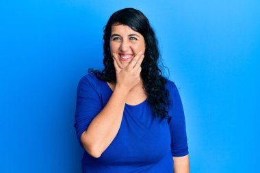 Artı mavi bir gömlek giyen esmer kadın kameraya kendinden emin bakıyor kollarını kavuşturmuş ve çenesini kaldırmış gülümsüyor. Olumlu düşünmek. 