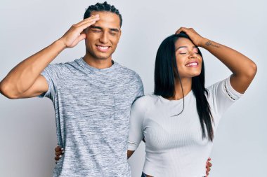 Gündelik kıyafetler giyen genç latin çift gülümseyerek saçlarına dokunarak el hareketleriyle çekici ve modaya uygun poz veriyorlar. 