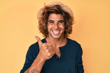 Yaz şapkası takan İspanyol genç adam elleriyle mutlu bir jest yapıyor. Kameraya bakıp başarıyı gösteren ifade. 