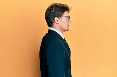 Yakışıklı, beyaz takım elbiseli, kravat takan, rahat bir görünüm takınan, kendine güvenen bir gülümsemesi olan beyaz bir adam.. 