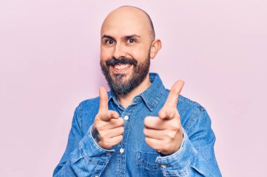 Gündelik giysiler giymiş genç yakışıklı adam mutlu ve komik yüzüyle kamerayı işaret ediyor. iyi enerji ve titreşimler. 