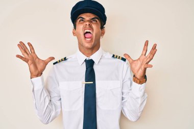 Genç İspanyol pilot üniforması giyen çılgın ve sinirli bir adam agresif bir ifadeyle bağırıyor ve kollarını kaldırıyor. hüsran kavramı. 