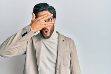 İş ceketi giyen ve gözlüklü genç İspanyol adam şok içinde yüzünü ve gözlerini kapayarak utangaç ifadesiyle parmaklarından bakıyor.. 