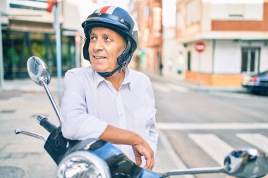 Kıdemli motosikletçi, şehirde moto miğfer takıp mutlu bir şekilde gülümsüyor..