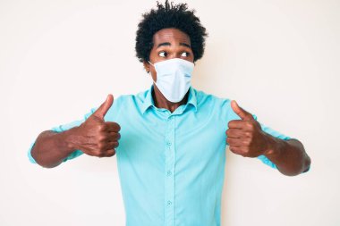 Yakışıklı Afro saçlı, tıbbi maske takan, sinirli ve öfkeli sinirli sinirli sinirli sinirli ve öfkeyle bağıran Afro-Amerikan bir adam. öfke ve agresif konsept. 