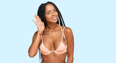 Bikini giyen güzel İspanyol kadın kulağına fısıldayarak dedikoduları ve dedikoduları dinliyor. Sağırlık kavramı. 