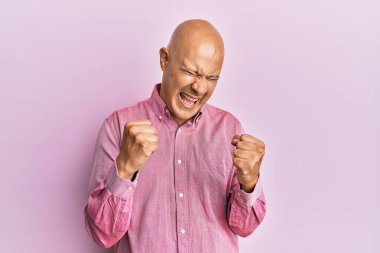 Orta yaşlı, kel bir adam pembe iş gömleği giyiyor. Başarılı olduğu için şaşırmış ve şaşırmıştı. Kolları havada ve gözleri kapalıydı. 