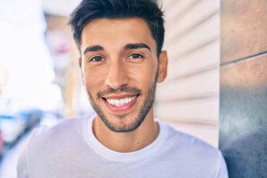 Genç Latin adam gülümseyerek şehirde mutlu mesut yürüyor..