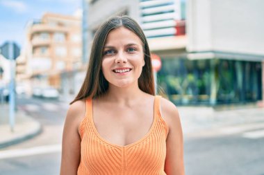 Genç ortadoğu kızı gülümseyerek şehirde mutlu mesut yürüyor..