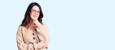 Güzel, genç, esmer, günlük kıyafetler ve gözlük takan, kameraya kendinden emin, kolları çapraz ve çenesi açık gülümseyen bir kadın. Olumlu düşünmek. 