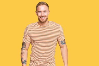 Genç İrlandalı sıradan kıyafetler giyen, pozitif ve mutlu görünen, kendine güvenen, gülümseyen, dişlerini gösteren genç bir adam. 