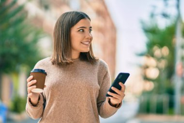 Genç İspanyol kadın akıllı telefon kullanıyor. Şehirde kahve içiyor..