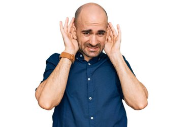 Gündelik giysiler giyen genç İspanyol adam iki elini de kulak hareketlerini duymaya çalışıyor. Dedikoduya meraklı. İşitme sorunu, sağır 