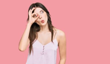 Genç, güzel, beyaz bir kız günlük kıyafetler giyiyor. Şaşırmış yüz ifadesiyle şaşırmış, parmaklarının arasından bakıyor. İnançsız ifade. 