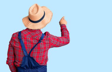 Yakışıklı Latin Amerikalı genç adam. Tamirci üniforması giyiyor. Geriye doğru poz veriyor. 