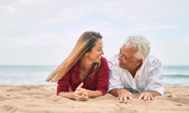 Orta yaşlı aşık bir çift kumsalda birlikte mutlu ve neşeli bir şekilde yatıyor.