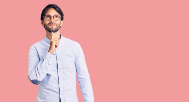 Yakışıklı, iş gömleği ve gözlük takan, şüpheye odaklanmış, çenesinde parmak olan ve kafasını kaldırıp merak eden bir İspanyol. 