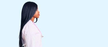 Doktor steteskop takan Afro-Amerikalı genç bir kadın profilini rahatlatmak için doğal bir yüz ifadesi ve kendine güvenen bir gülümseme takınıyor.. 