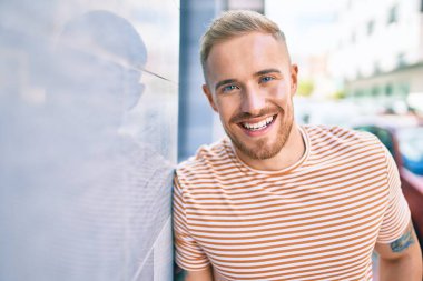 Genç İrlandalı gülümseyen mutlu adam şehrin duvarına yaslanıyor..