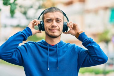 Genç İspanyol adam gülümseyerek şehirde mutlu mesut dikiliyor.