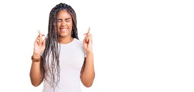 Saçları örgülü genç Afro-Amerikalı kadın umut ve gözleriyle gülümseyerek el kol hareketi yapıyor. Şans ve batıl inançlar. 