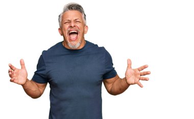 Orta yaşlı, gri saçlı, sıradan kıyafetler giyen çılgın ve kızgın bir adam agresif bir ifadeyle bağırıyor ve kollarını kaldırıyor. hüsran kavramı. 