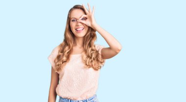 Sarışın, güzel, beyaz bir kadın. Sıradan kıyafetler giyiyor. El hareketleriyle gülümsüyor.. 